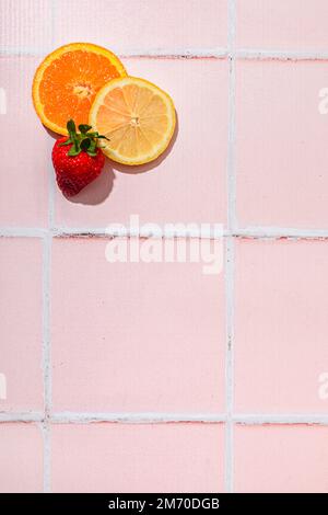 Orangenscheibe, Zitronenscheibe und Erdbeere auf pinkfarbenem Hintergrund, sommerliche Atmosphäre, Kopierbereich Stockfoto
