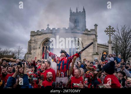 Der zeremonielle Narr, James Chatwin, hält eine Rede während des Rauchens des Narr, während er den Haxey Hood beginnt, eine alte Tradition aus dem 14. Jahrhundert im Dorf Haxey in North Lincolnshire. Teams, die Pubs aus zwei lokalen Dörfern, Haxey und Westwoodside, vertreten, kämpfen um die Kapuze - ein Lederschlauch - für ihren Pub-Vermieter. Die Haube wird in die Menge geworfen und nach vorn in Richtung der Pubs geschwenkt, die als Tore bekannt sind, ohne dass sie getreten oder geworfen wird. Der preisgekrönte Pub zeigt die Kapuze bis zum nächsten Jahr. Foto: Freitag, 6. Januar 2023. Das Spiel geht zurück Stockfoto