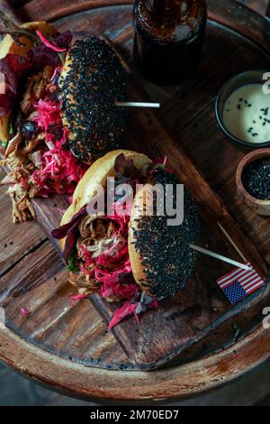 Burger mit Schweinefleisch und schwarzem Sesam mit knusprigem Apfelsalat, eingelegtem Rotkohl, knusprigem Apfelsalat, amerikanischer Flagge, Unabhängigkeitstag der USA Stockfoto