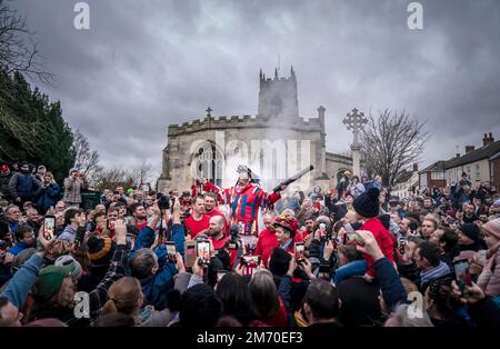 Der zeremonielle Narr, James Chatwin, hält eine Rede während des Rauchens des Narr, während er den Haxey Hood beginnt, eine alte Tradition aus dem 14. Jahrhundert im Dorf Haxey in North Lincolnshire. Teams, die Pubs aus zwei lokalen Dörfern, Haxey und Westwoodside, vertreten, kämpfen um die Kapuze - ein Lederschlauch - für ihren Pub-Vermieter. Die Haube wird in die Menge geworfen und nach vorn in Richtung der Pubs geschwenkt, die als Tore bekannt sind, ohne dass sie getreten oder geworfen wird. Der preisgekrönte Pub zeigt die Kapuze bis zum nächsten Jahr. Foto: Freitag, 6. Januar 2023. Das Spiel geht zurück Stockfoto