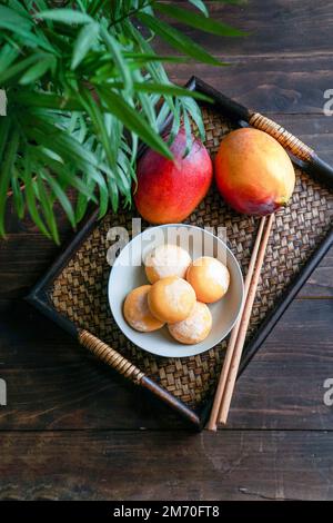 japanische Mango-Mochi-Kuchen mit Eiscreme auf einem klassischen asiatischen Holztablett Stockfoto
