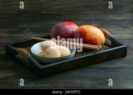 japanische Mango-Mochi-Kuchen mit Eiscreme auf einem klassischen asiatischen Holztablett Stockfoto