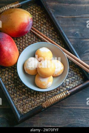 japanische Mango-Mochi-Kuchen mit Eiscreme auf einem klassischen asiatischen Holztablett Stockfoto