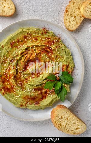 Avocado hummus gewürzt mit Sesam, Paprika und Petersilie. Das Gericht wird mit Toast serviert. Stockfoto