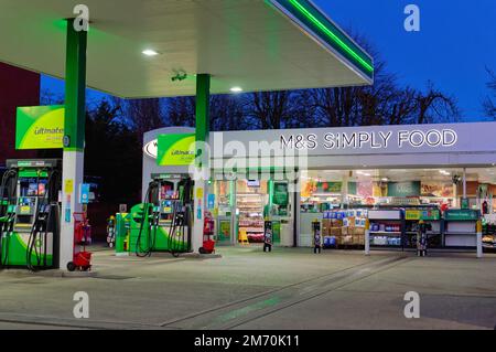 Der Vorplatz der BP-Tankstelle in der Abenddämmerung mit einem Marks and Spencer Simply Food Outlet Shop in Shepperton High Street Surrey England Stockfoto