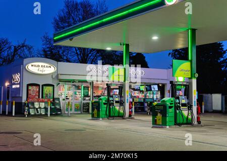 Der Vorplatz der BP-Tankstelle in der Abenddämmerung mit einem Marks and Spencer Simply Food Outlet Shop in Shepperton High Street Surrey England Stockfoto