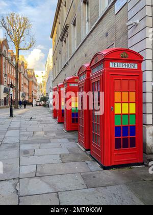 Rote Telefonzellen mit LGBTQ-Regenbogenfarben in London- LONDON, Großbritannien - 20. DEZEMBER 2022 Stockfoto