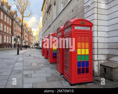 Rote Telefonzellen mit LGBTQ-Regenbogenfarben in London- LONDON, Großbritannien - 20. DEZEMBER 2022 Stockfoto