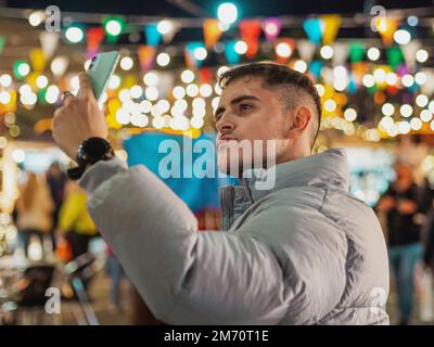 Eine Nahaufnahme eines jungen Mannes, der ein Selfie auf einem Bokeh-Hintergrund macht Stockfoto