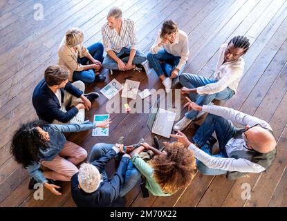 Kreative Geschäftsleute, die eine Team-Building-Sitzung abgehalten haben, gemischte Altersgruppen von Designern, die gemeinsam an Strategien arbeiten, Brainstorming im Team Stockfoto