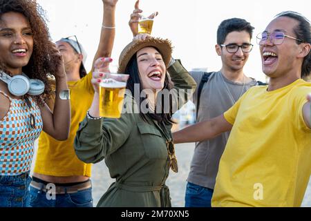 Fröhliche Freunde jubeln und trinken Cocktails auf der Strandparty im Freien, junge Leute haben Spaß am Wochenende im Urlaub, Jugendleben und Reise destin Stockfoto