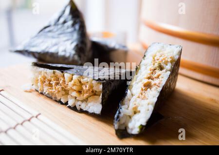 Thunfisch Onigiri. Onigiri, auch bekannt als Omusubi, ist ein japanisches Gericht, das aus einer Kugel Reis besteht, die gefüllt oder mit anderen Zutaten vermischt ist. Stockfoto