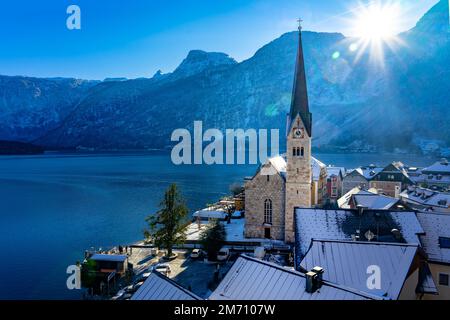 Schöne sonnige Stadtlandschaft der besonderen Stadt Hallstatt in Österreich Salzkammergut verschneite Winterberge und See und Kirche. Stockfoto