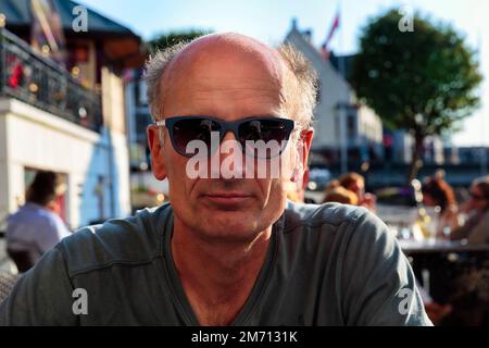 Best Ager, Porträt mit Sonnenbrille, leger, unrasiert, sitzt im Biergarten, Norwegen Stockfoto