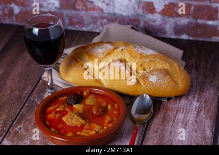 Tonauflauf mit eingekochtem, typisch spanischem Essen im Madrider Stil auf einem Holztisch mit einer Backsteinwand im Hintergrund Stockfoto