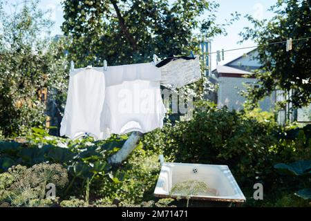 Gewaschene Kleidung an Wäscheleinen wird im Dorf an einem sonnigen Tag im Sommer getrocknet Stockfoto