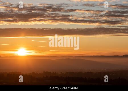 sonnenaufgang mit Sonnenschein in die Kamera in deutschland schwäbien mit verschwommener Landschaft Stockfoto