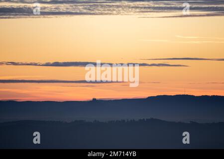 Sonnenaufgang mit rotem orangefarbenem Himmel vor Sonnenaufgang in deutschland schwäbien mit schloss hohenzollern am Horizont Stockfoto