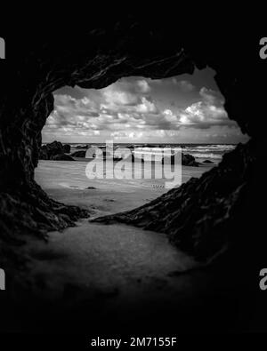 Eine vertikale Graustufenaufnahme des Meeres und des Strandes aus der Höhle Stockfoto
