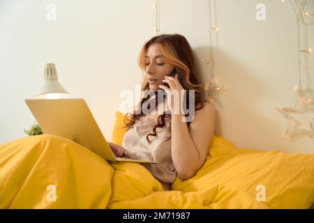 Eine Frau, die im Schlafzimmer telefoniert Stockfoto