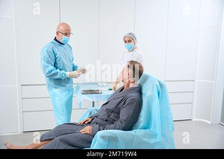 Professionelles medizinisches Personal bereitet sich auf die Behandlung des Patienten im Krankenhausmantel vor Stockfoto