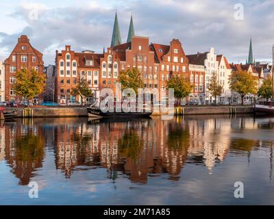 Historisches Schiff am Ufer der Trave und dahinter die Backsteingebäude Alte Hanseatische Häuser in der UNESCO-Weltkulturerbestätte Lübeck, Hansestadt Stockfoto