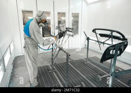 Männchen, der in der Garage Farbrestaurationen für Autoteile durchführt Stockfoto