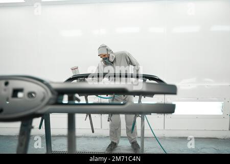 Männlicher im Beatmungsgerät, der die Farbe von Autoteilen restauriert Stockfoto