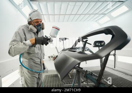 Ein erwachsener Mann, der für Autoteile Farbrestaurationen durchführt Stockfoto