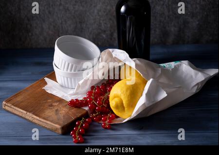 Frisch gekaufte Zitronen und rote Johannisbeeren in Papiertüte und weiße Gratiniergerichte Stockfoto