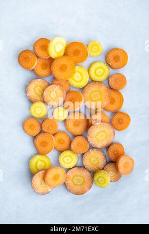 Eine Nahaufnahme der in Scheiben geschnittenen gelben und orangefarbenen Möhren, die in einem geometrischen Muster über dem Kopf zu sehen sind. Stockfoto