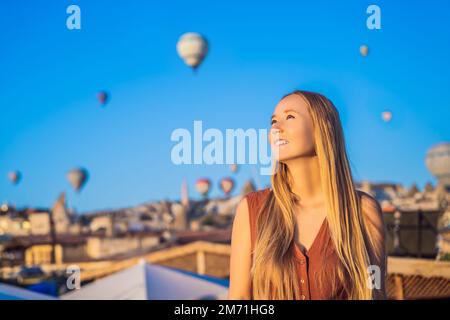 Eine Touristin, die Heißluftballons in Kappadokien, Türkei, ansieht. Happy Travel in Turkey Concept. Eine Frau auf einem Berggipfel, die eine wunderbare Aussicht genießt Stockfoto