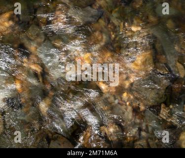 Muster im fließenden Wasser eines Flusses. Aufnahmen mit einer langsameren Verschlusszeit für einen abstrakten Look. Stockfoto