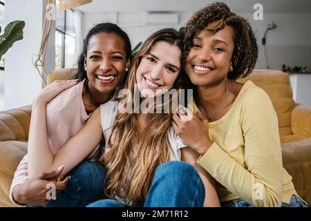 Porträt von gemischtrassigen Freundinnen, die zu Hause vor der Kamera lächeln Stockfoto