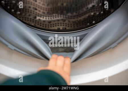 Schimmel im Gummi um die Waschmaschine herum, schlechter Geruch. Schimmel in Gummidichtung in einer Waschmaschine. Verschmutztes, schimmeliges Dichtungsgummi der Waschmaschine Stockfoto