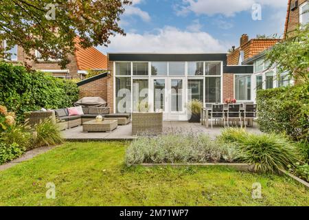 Der hintere Garten mit Terrassenmöbeln und Pflanzen im Vordergrund, mit Blick auf den Hinterhof Stockfoto