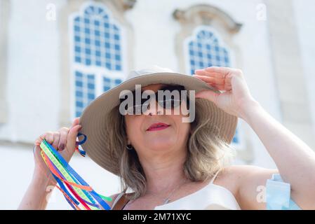 Salvador, Bahia, Brasilien - 06. Januar 2023: Katholische Frau hält während der Messe farbenfrohe Bänder gegen die Kirche Senhor do Bonfim. Stadt Salvador, Ba Stockfoto