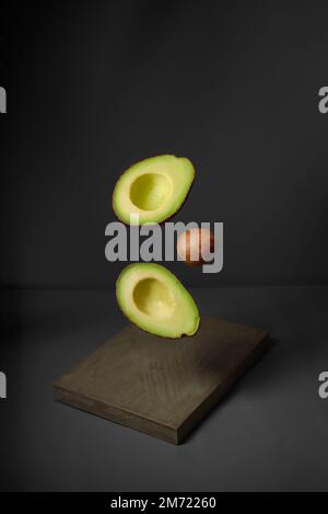 Avocado in der Luft rustikaler Holztisch. Rohe Früchte mit gesunder grüner Nahrung. Konzept: Fruchtfliege, ohne Leute Stockfoto