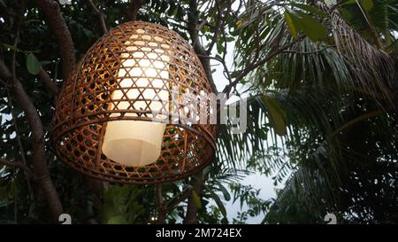 Lampenlampe aus gewebtem Bambusbezug, die im Baum hängt Stockfoto