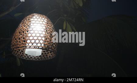 Lampenlampe aus gewebtem Bambusbezug, die im Baum hängt Stockfoto