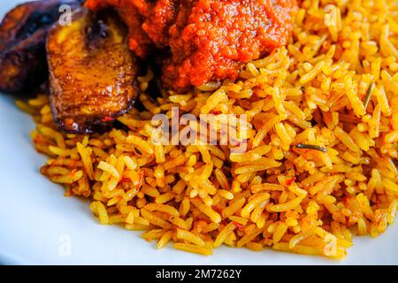 nigerianischer Jollof Reis serviert mit Plantain und Eintopf Stockfoto
