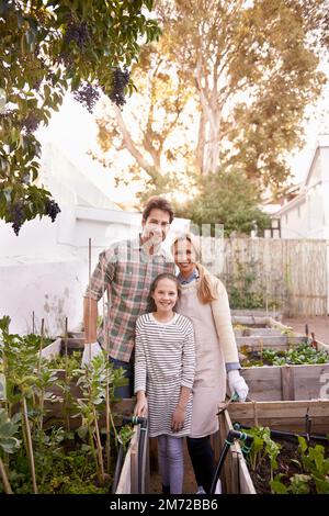 Diese Familie wird grün. Porträt einer glücklichen Familie, die zusammen im Garten gärtnert. Stockfoto