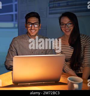 Bis spät in die Nacht arbeiten. Zwei Kollegen, die bis in die Nacht arbeiten. Stockfoto