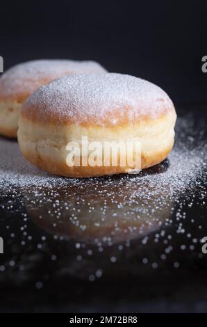 Deutsche Donuts berliner mit Puderzucker auf schwarzem Hintergrund Stockfoto