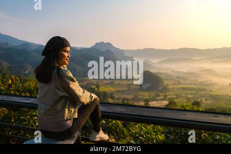 Frauen, die den Sonnenaufgang mit Nebel und Nebel in den Phu Langka Bergen im Norden Thailands beobachten, Bergblick auf den Phu Langka Nationalpark in der Provinz Phayao Stockfoto