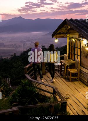 Ein paar Männer und Frauen beobachten den Sonnenaufgang mit Nebel und Nebel in den Phu Langka Bergen im Norden Thailands, Mountain View des Phu Langka Nationalparks in der Provinz Phayao Stockfoto