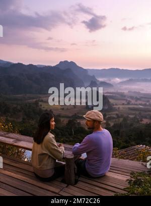 Ein paar Männer und Frauen beobachten den Sonnenaufgang mit Nebel und Nebel in den Phu Langka Bergen im Norden Thailands, Mountain View des Phu Langka Nationalparks in der Provinz Phayao Stockfoto
