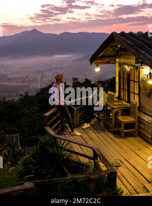 Ein paar Männer und Frauen beobachten den Sonnenaufgang mit Nebel und Nebel in den Phu Langka Bergen im Norden Thailands, Mountain View des Phu Langka Nationalparks in der Provinz Phayao Stockfoto