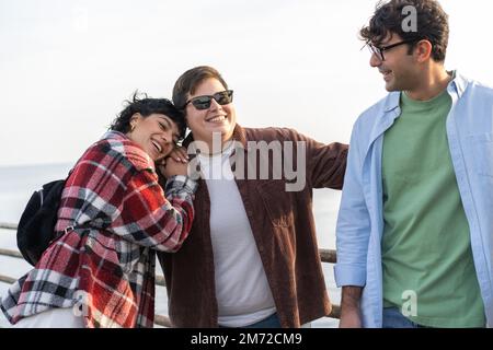 Eine Gruppe von vier Freunden, die zusammen Spaß haben. Zwei Frauen und ein Mann, die lachen und ihre Zeit am Meer genießen - verschiedene Menschen Lebensstil Konzept Stockfoto