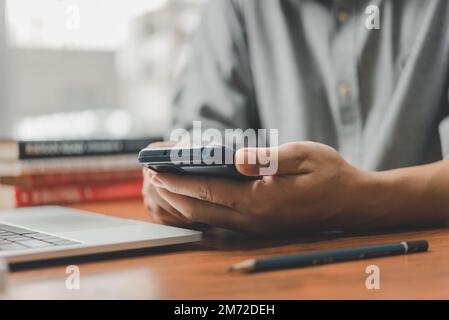 Mann mit Handy und Laptop im Büro. Freiberufler bei der Arbeit. Stockfoto